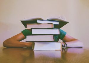 An image of student hidden behind a big stack of books