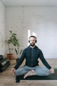 Man on the floor practicing mindfulness with legs crossed and arms out