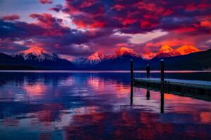 View of a colorful red, orange, pink, and purple, clouded sky, reflecting over the still water.