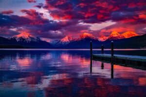 View of a colorful red, orange, pink, and purple, clouded sky, reflecting over the still water.
