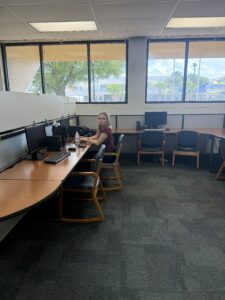 A girl is sitting at a computer inside the library. She is studying.