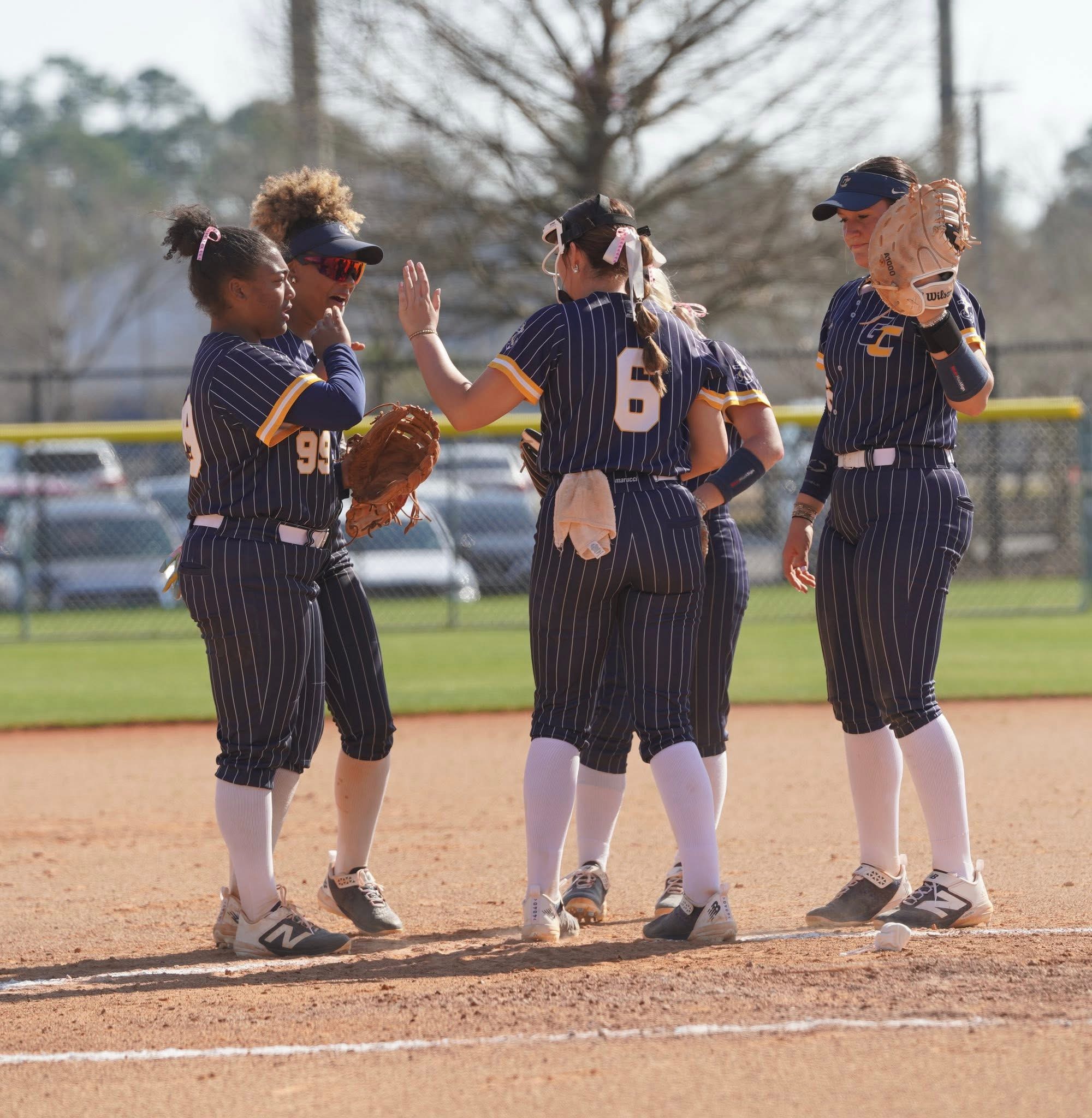 Gulf Coast State College softball infielders huddle and high-five before the start of an inning during the 2026 season.