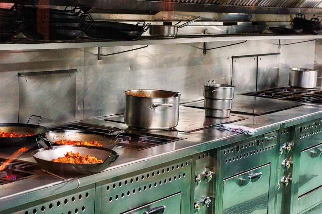 A restaurant kitchen with pots and pans steaming
